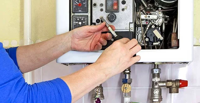 Technician servicing the internal components of a wall-mounted tankless water heater